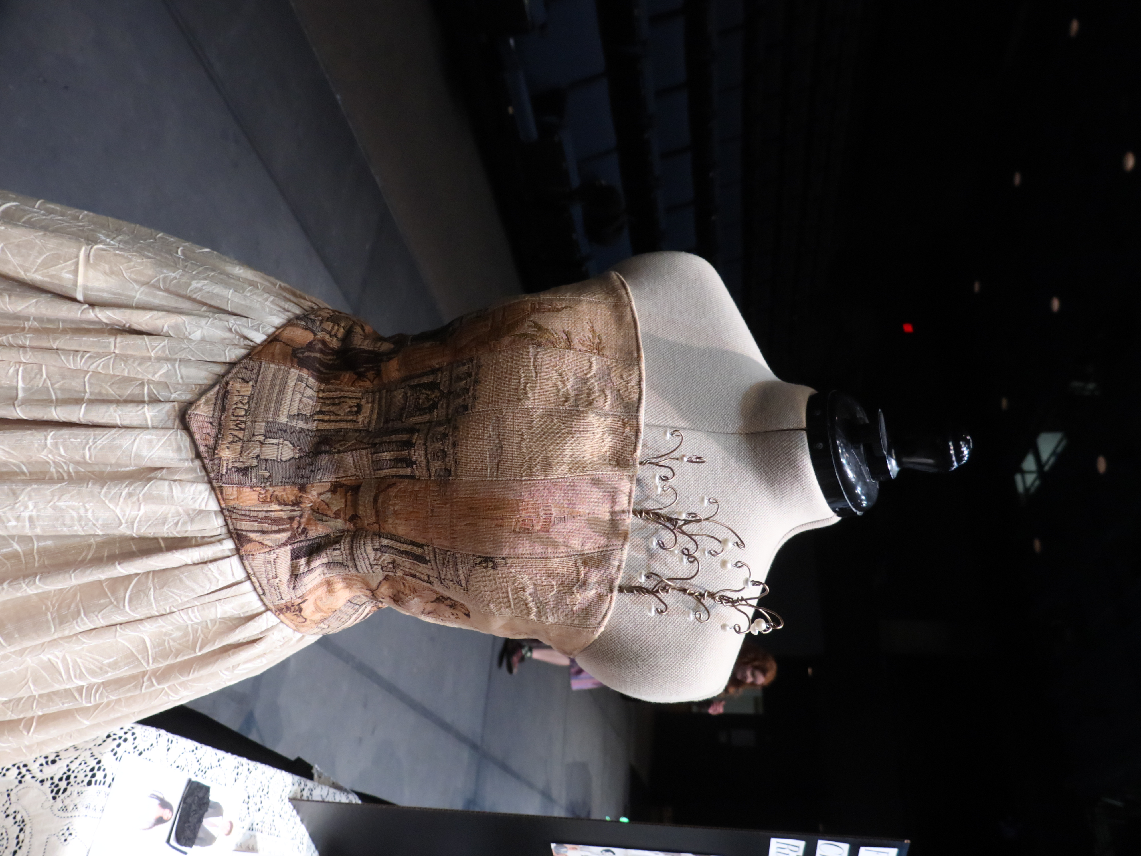 Photo of a strapless dress with a corset bodice, full skirt, and metal flowers peeking out above the top.