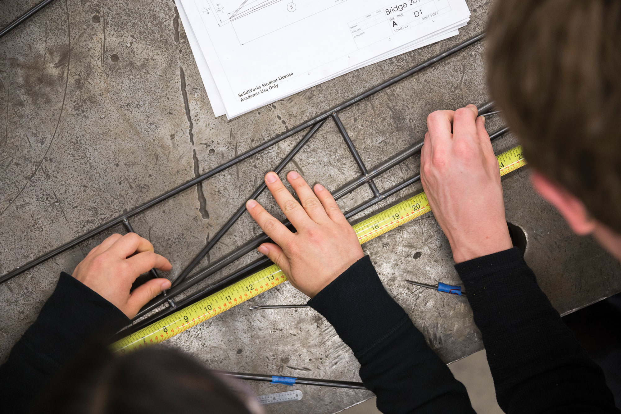 Aerial photo overlooking two students' hands with a ruler and other tools