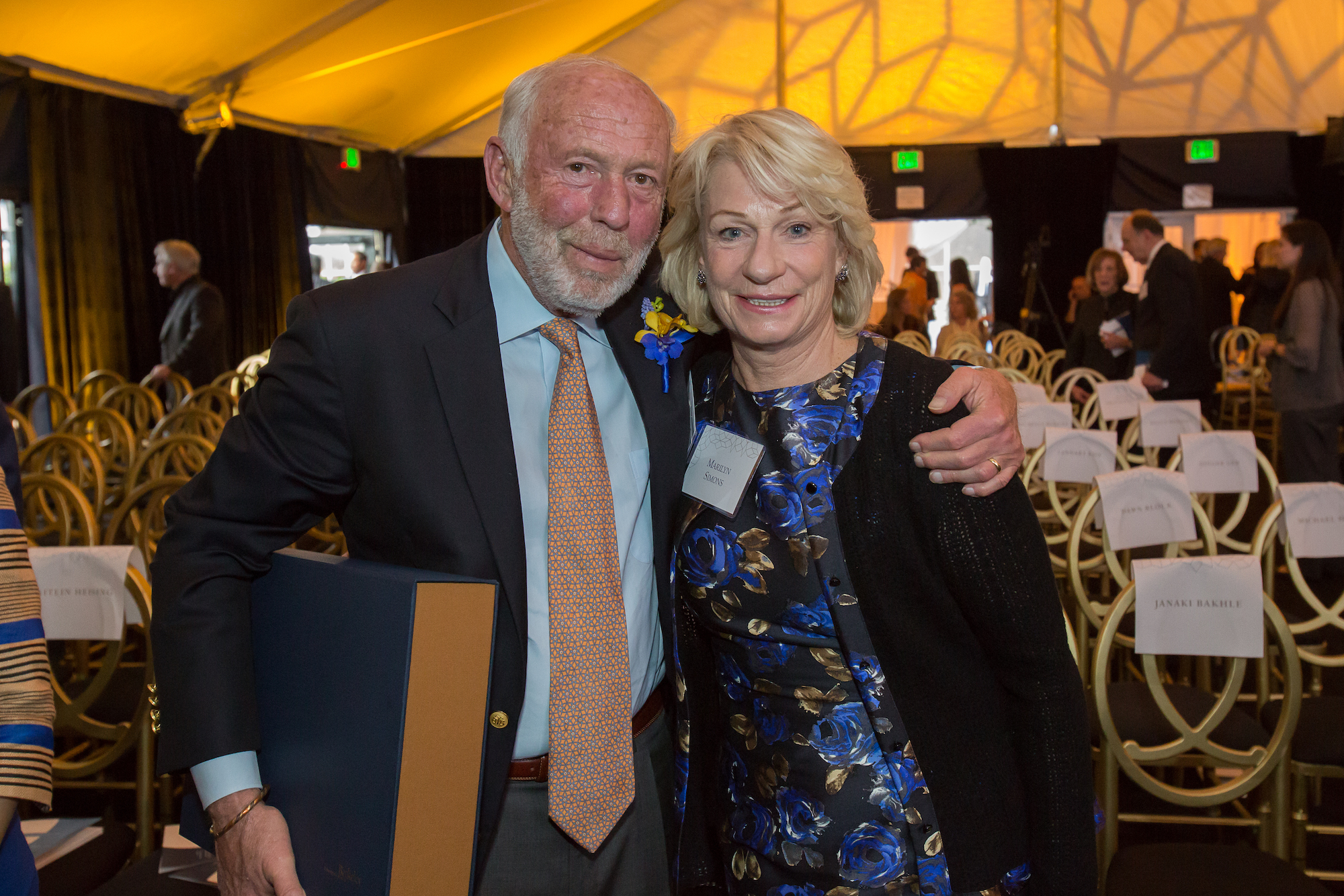Color photo of Jim and Marilyn smiling at the camera, his arm around her shoulder, at a gala event.