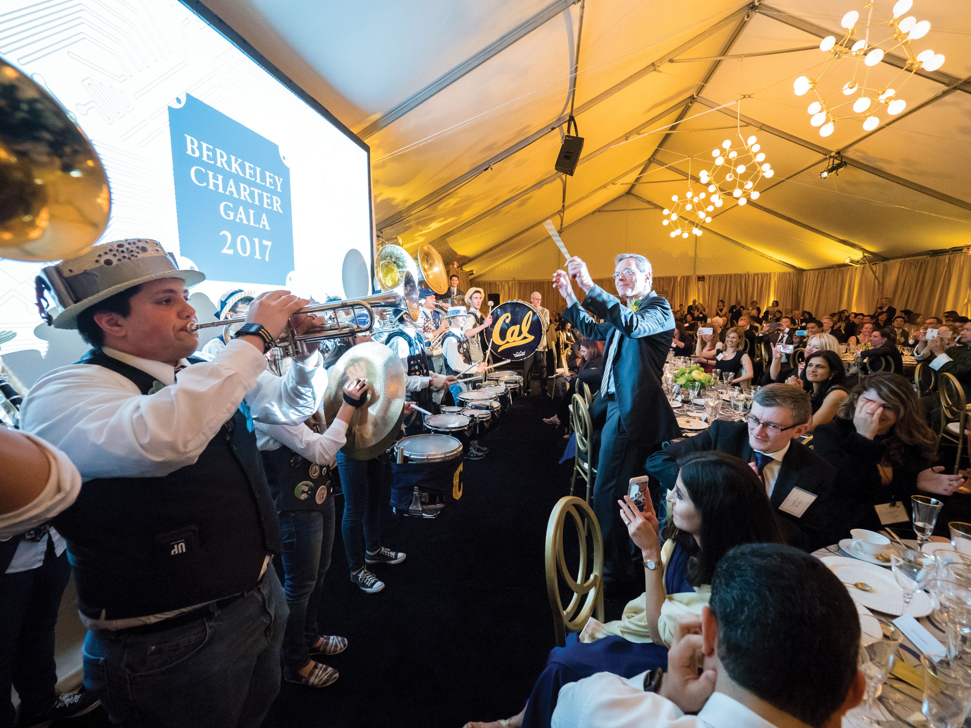 Photo of members of the Cal Band playing in front of a screen reading 