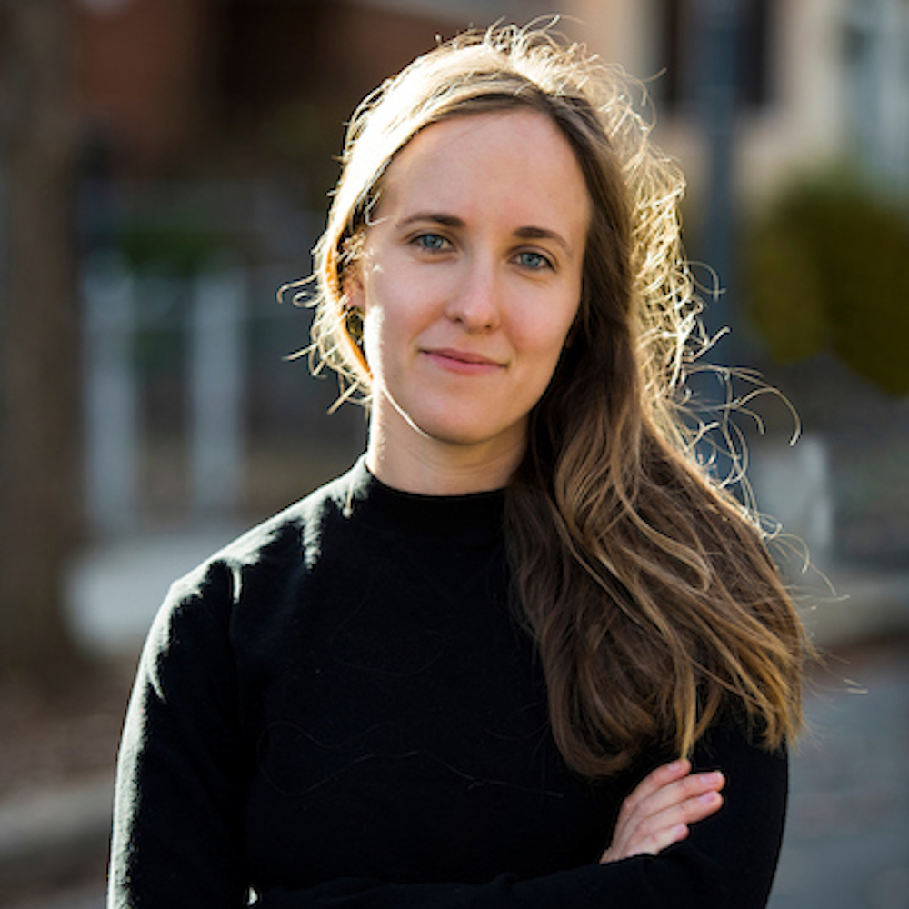 Photo of Linda with her arms crossed and her long hair swept to one shoulder.