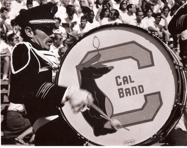 Black and white photo of Mark in uniform carrying a giant drum emblazoned with the letter C and an illustration of a bear.