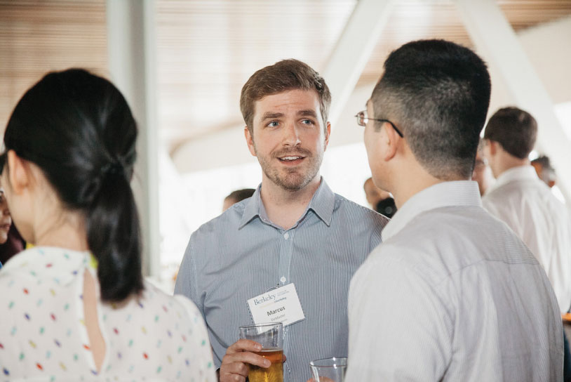 Photo of three people at a networking event, one wears a name tag and faces the camera