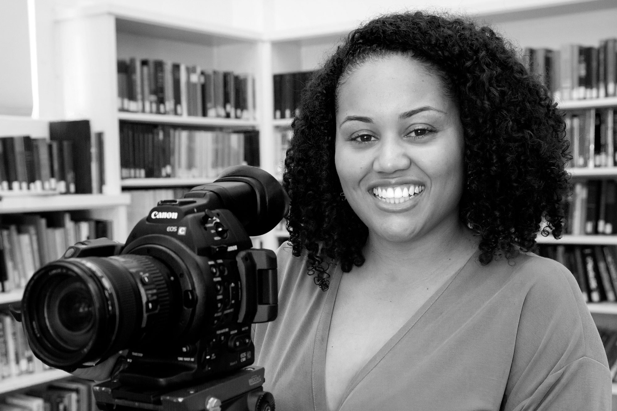 Photo of a smiling grad student posing with video camera