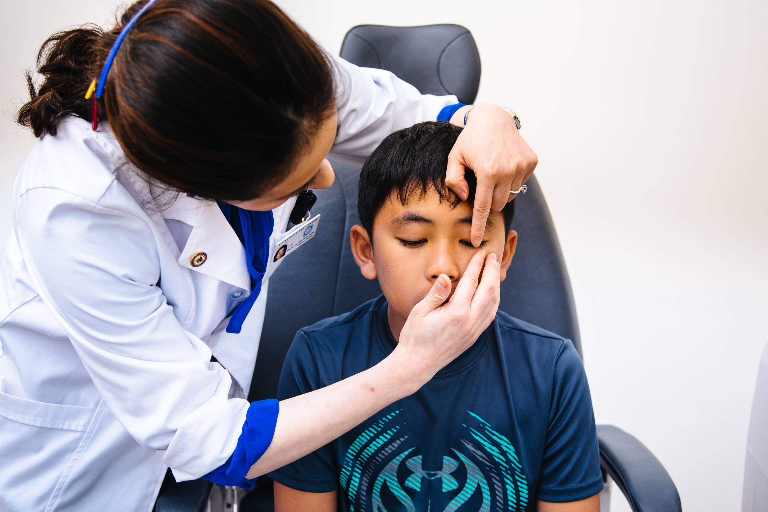 Photo of a woman in a white optometrist's coat fitting a child with a lens.
