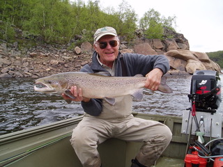 Photo of Moore in the back of a boat proudly holding a large fish.