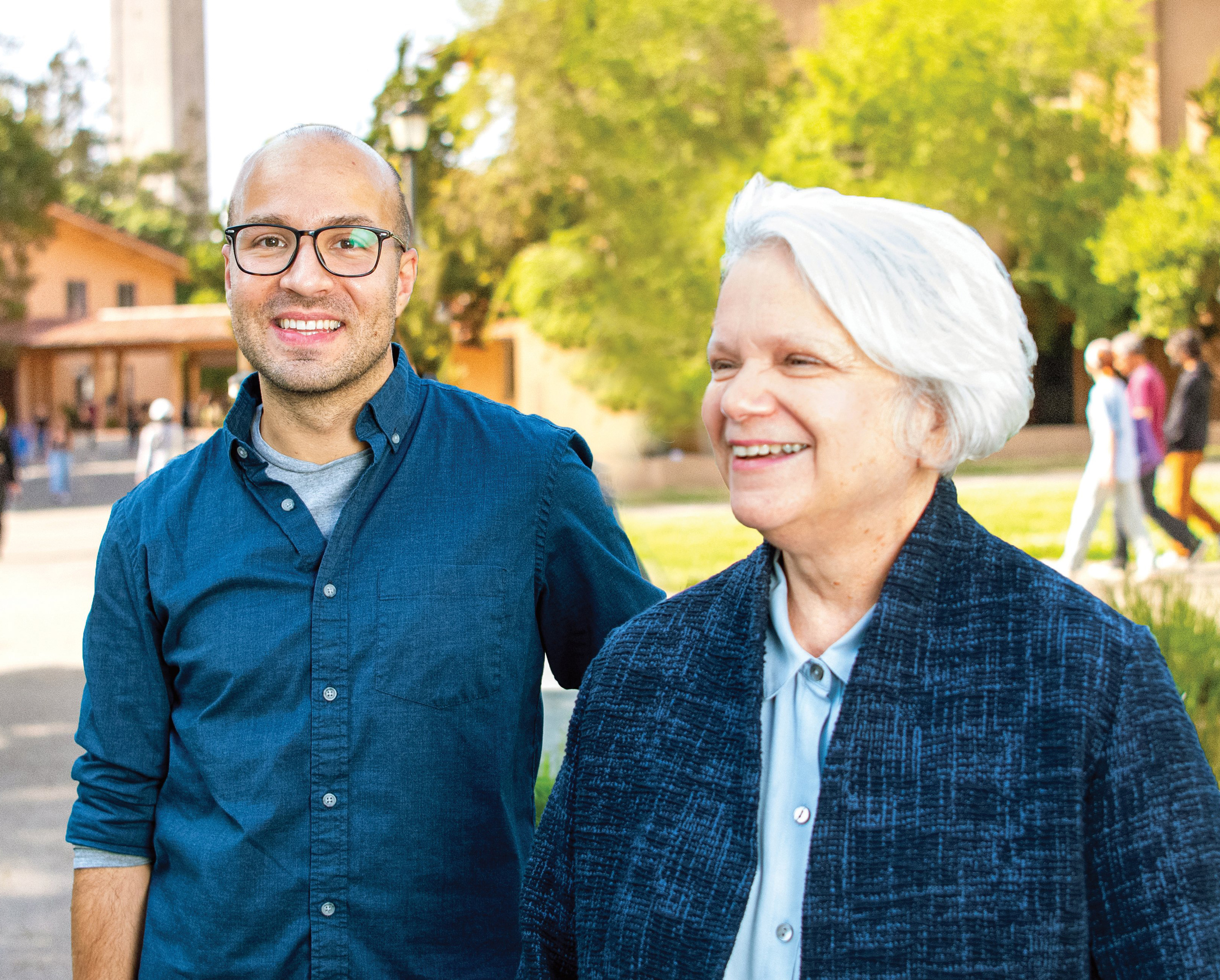 Photo of Pol standing next to Louise with the Campanile in the background. Both are wearing different shades of blue and smiling.