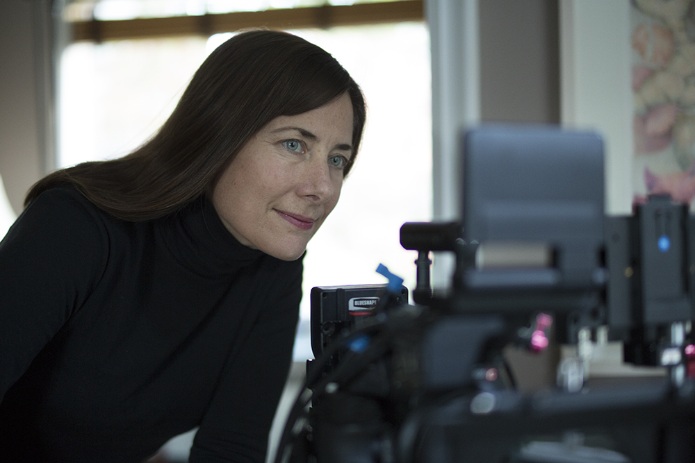 Color photo of filmmaker Redfearn in closeup, with a video camera