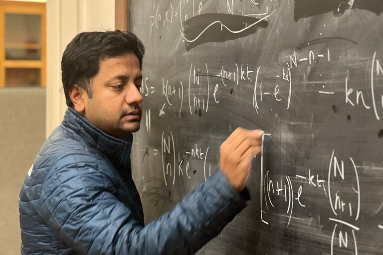 Color photo of Karthik Shekhar writing on a chalkboard