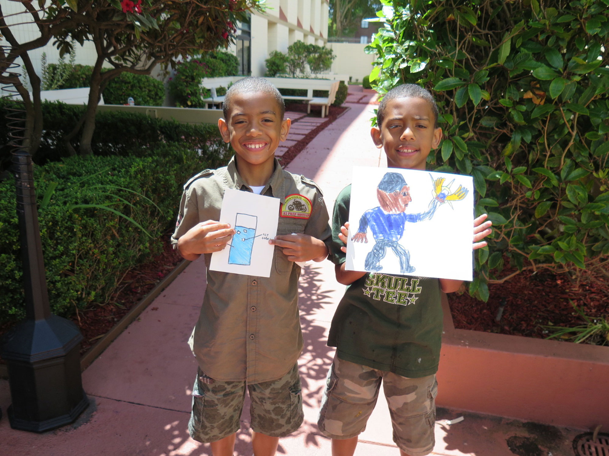 Photo of two boys holding up drawings from the books they wrote.