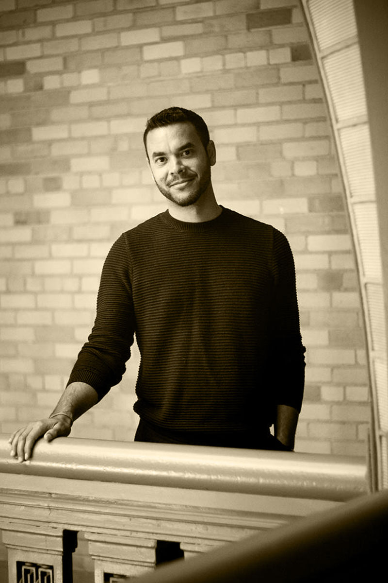 Photo of Brumfield standing on a balcony against a brick wall.