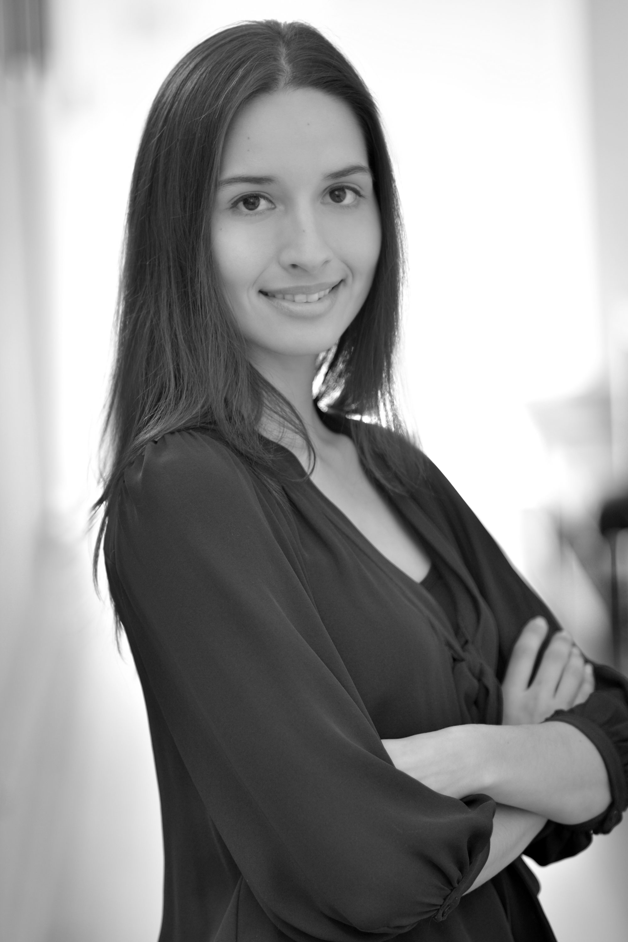 Black and white photo of student smiling and posing with crossed arms