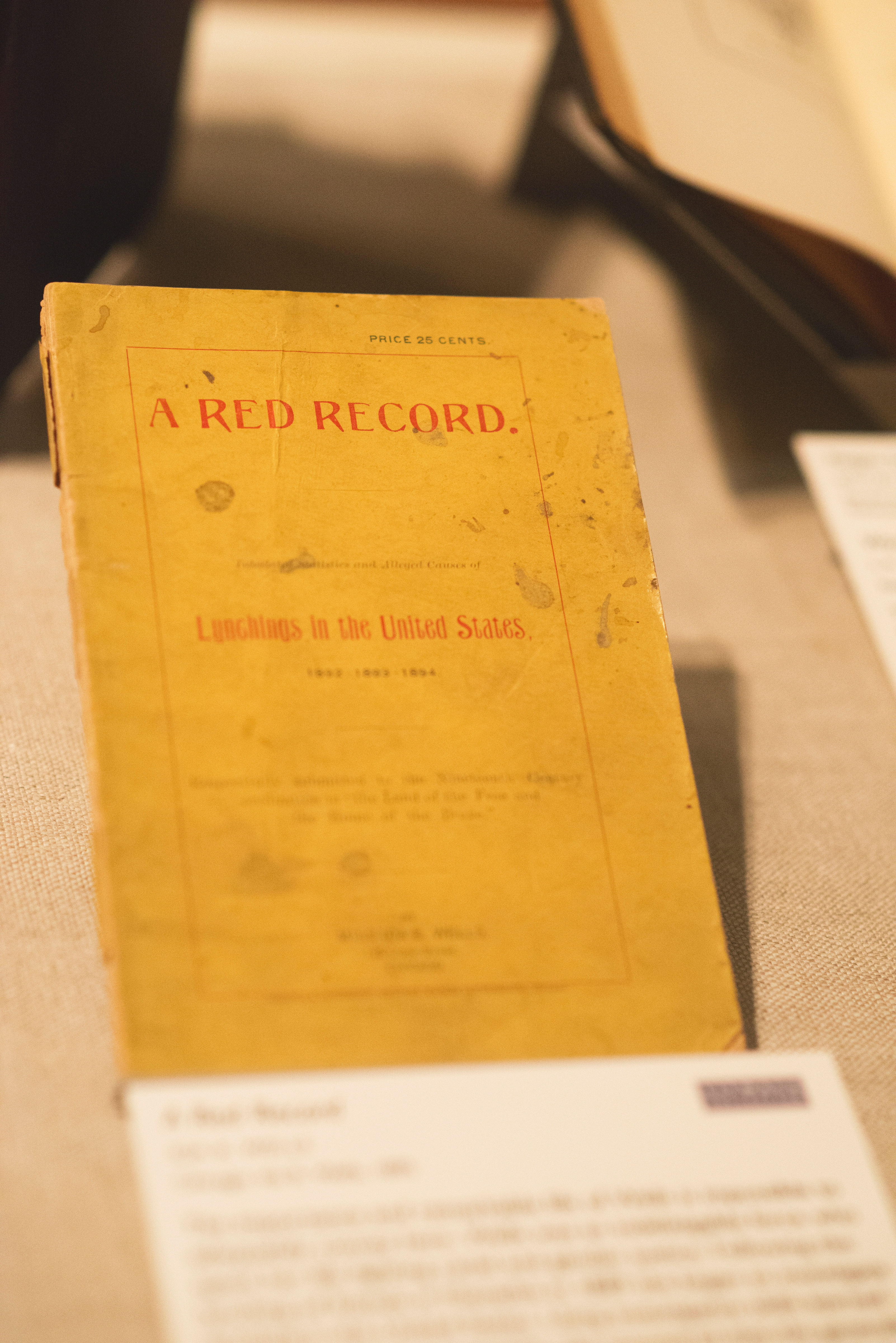 Color photo of a gold-colored pamphlet, featuring red writing on the cover