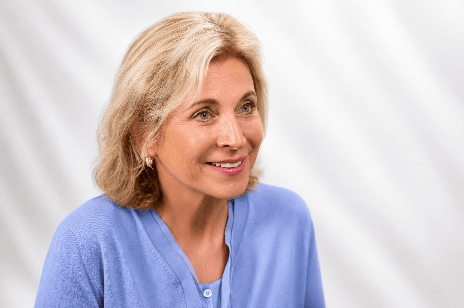 A color photo of Lynn, who is wearing a periwinkle blue cardigan and has blonde hair, against a white background.