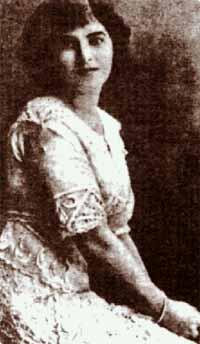 Sepia-toned photo of a seated woman with shoulder-length dark hair and an ornate dress.