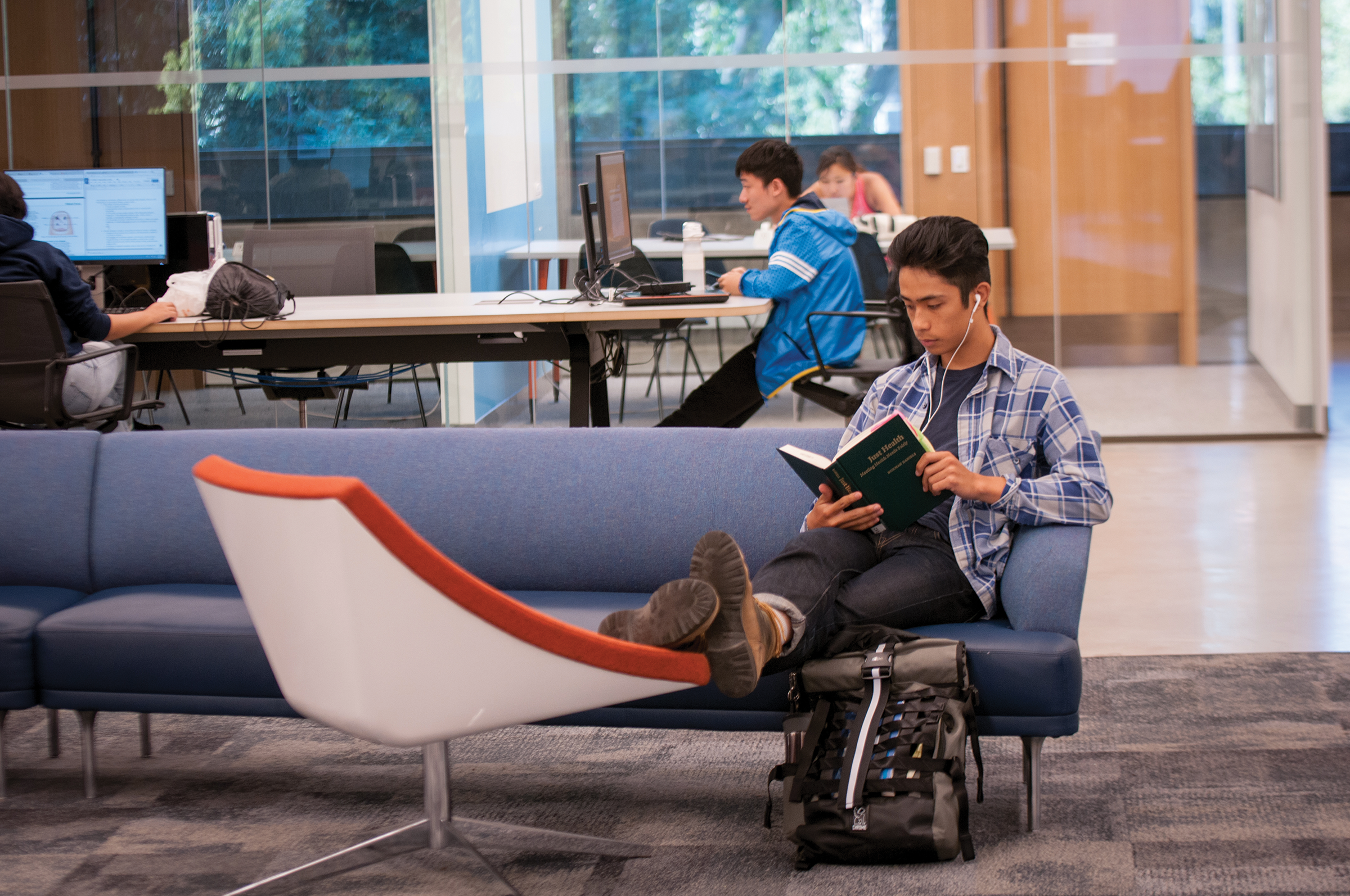 Photo of a student kicking back in a comfy chair and reading.