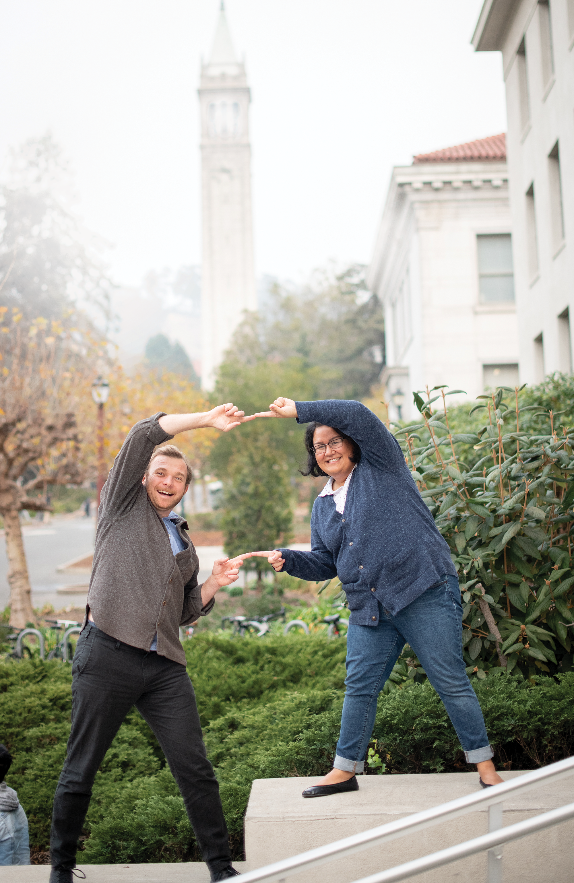 Photo of Krzysztof and Bria standing side by side with a misty Campanile in the background forming a circle of connection with their hands.