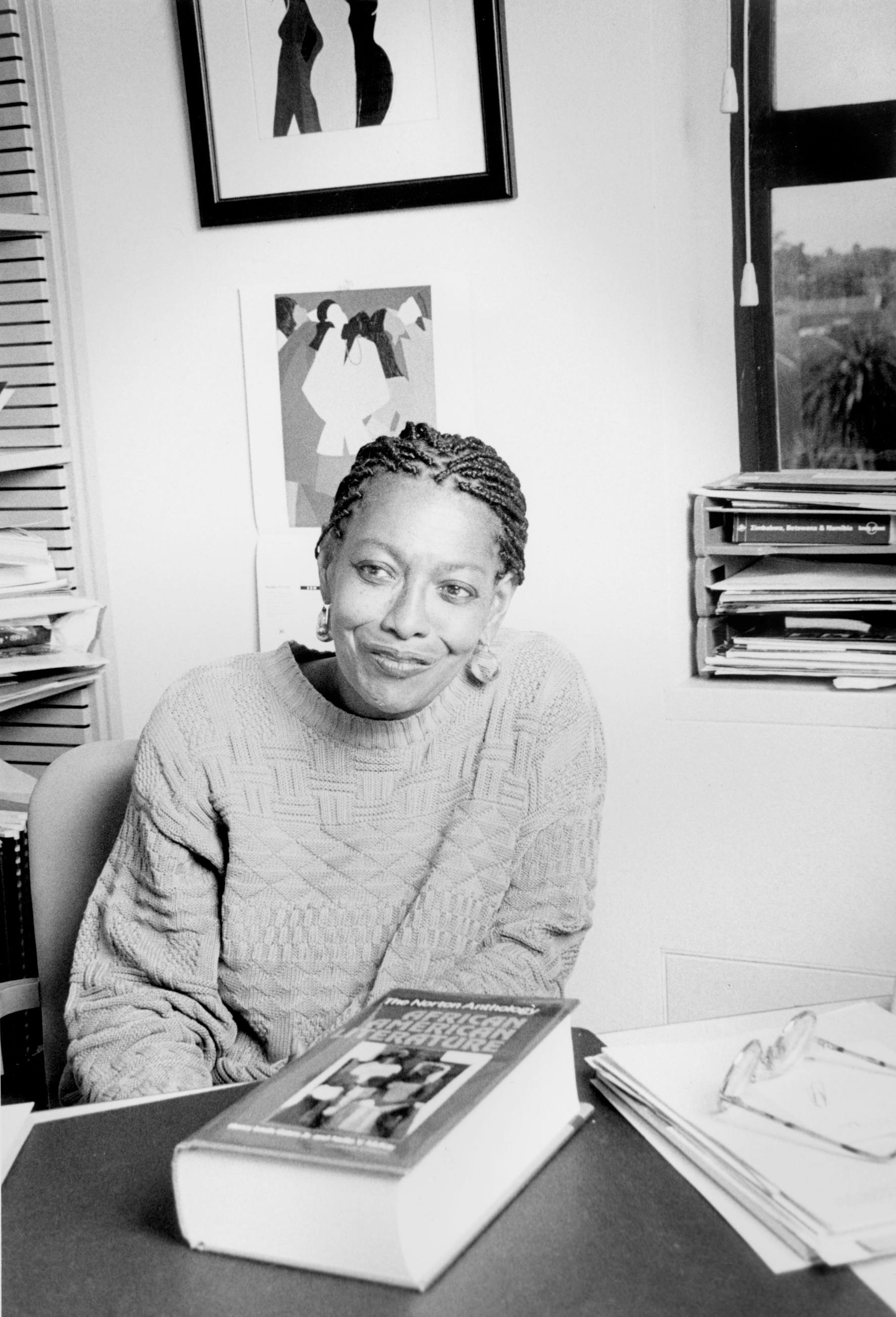 Photo of Barbara Christian smiling at a table with a large book in front of her.