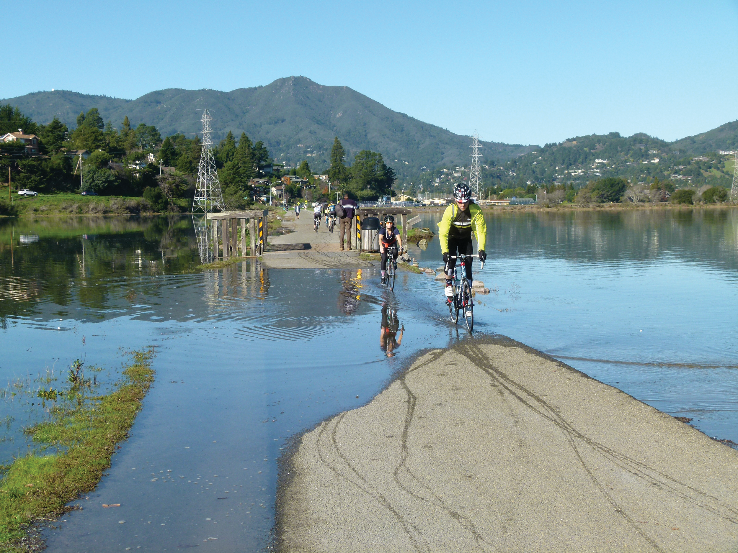 Photo of bikers rolling through a flooded pathway.