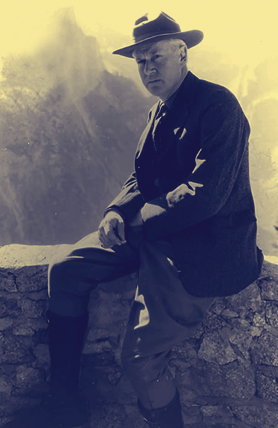 Historic photo of Stephen Mather in a hat overlooking a mountain range