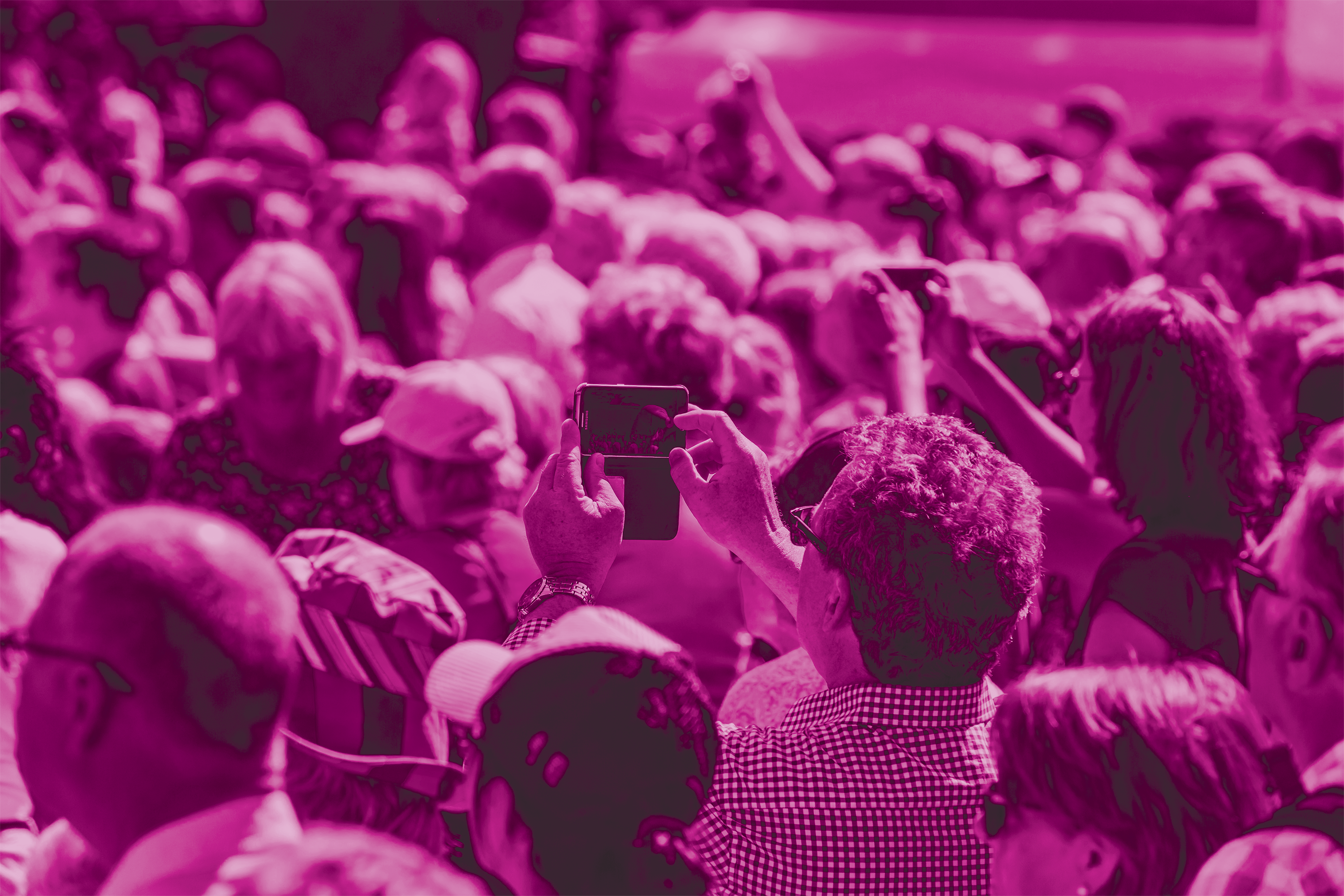 Photo of a man taking a photo with his phone in a large crowd.