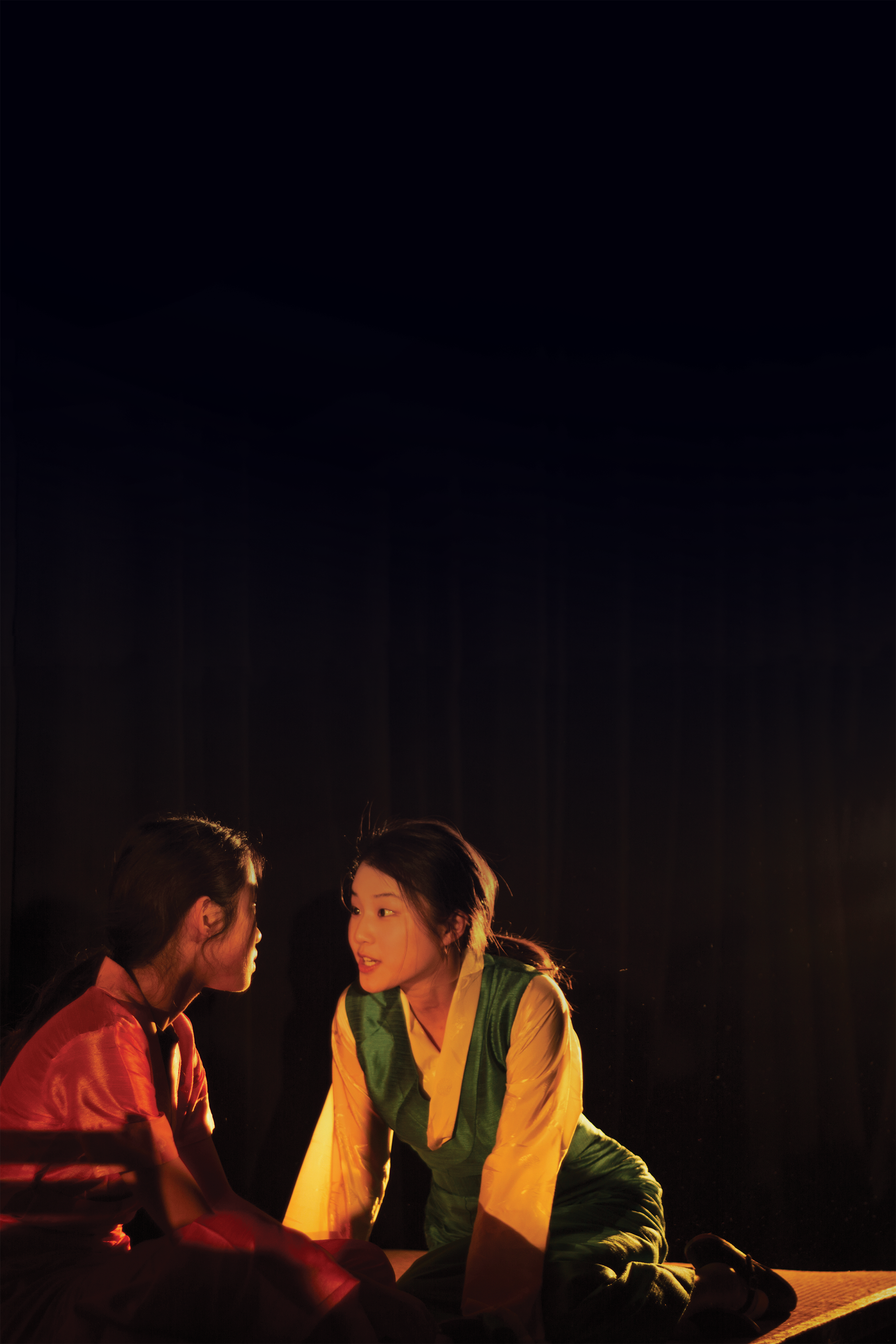 A photo of two women kneeling on the ground speaking to one another.