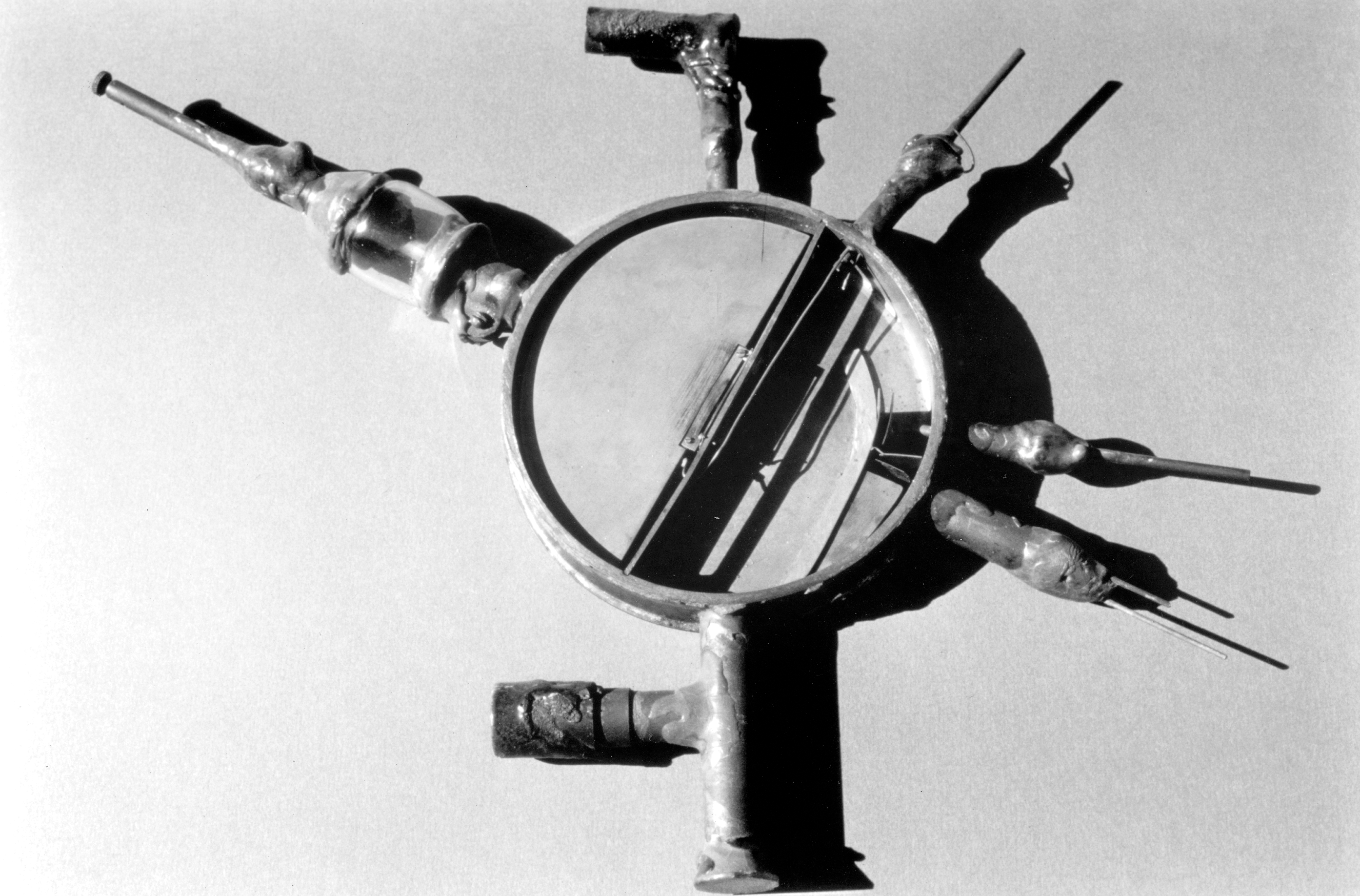 Black-and-white photo of the cyclotron, which looks like a magnifying glass with additional appendages.