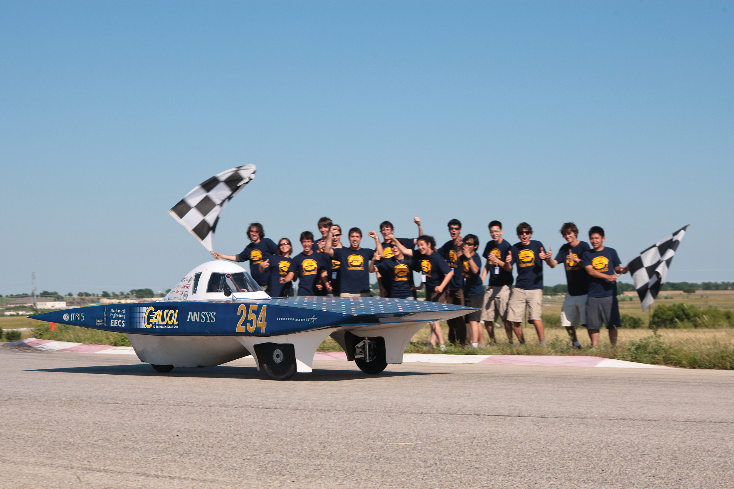 The group is cheering in front of one of its car inventions.