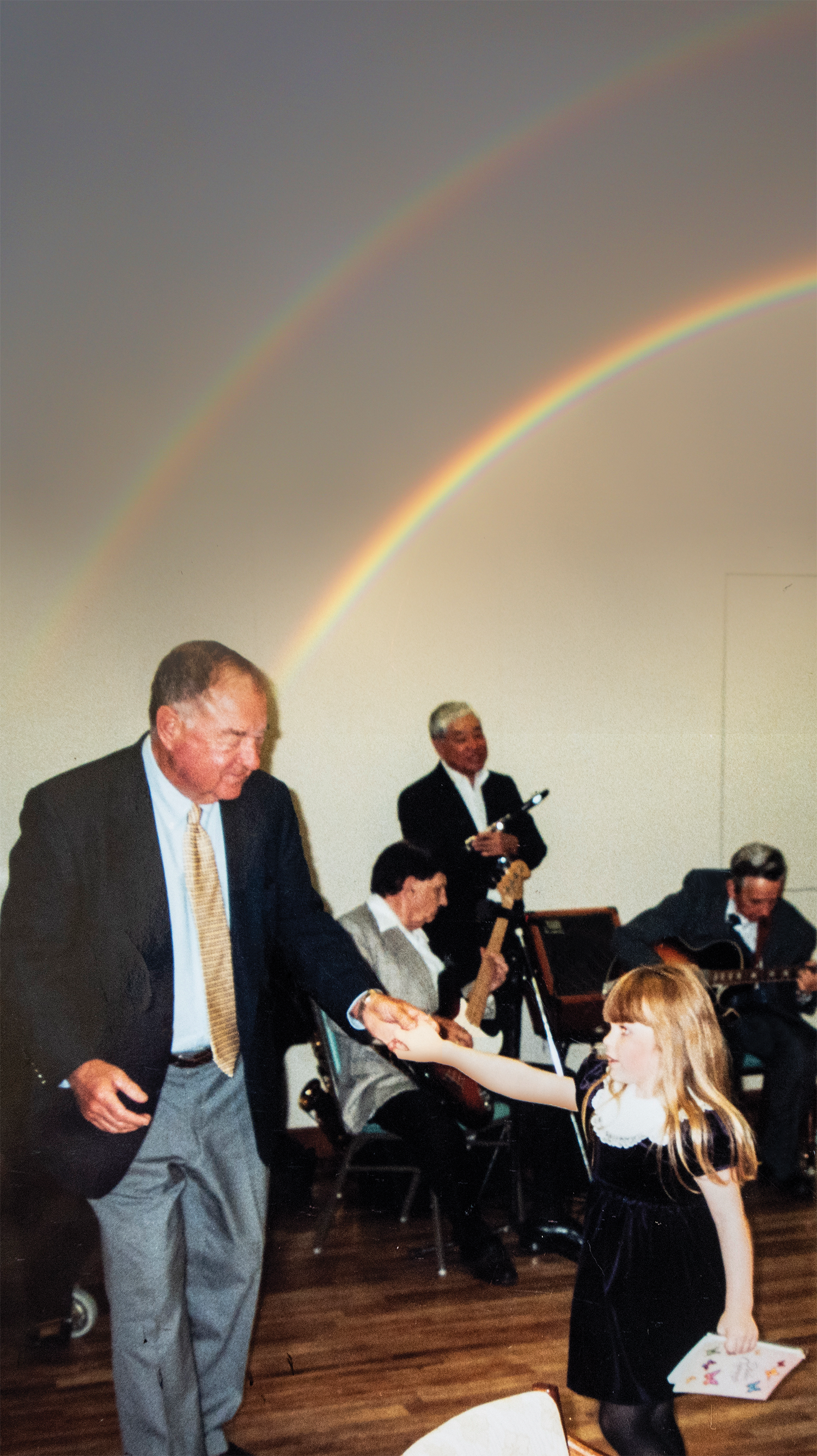 Autumn and her grandfather, a Cal alum, dancing with a rainbow on the wall behind them
