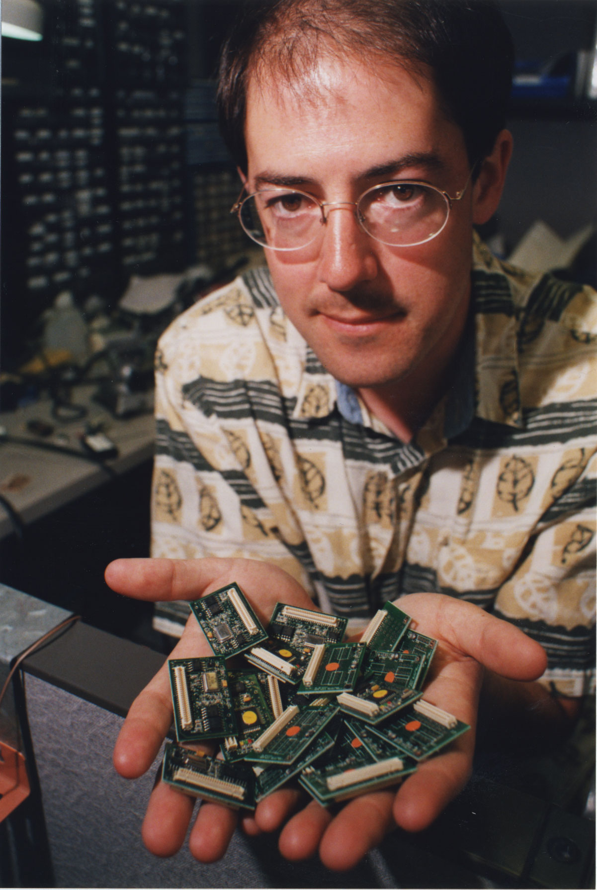 Photo of Kris Pister holding a handful of computer chips out as he looks intently at the camera