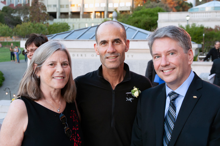 Photo of three people standing and smiling into the camera in front of the 