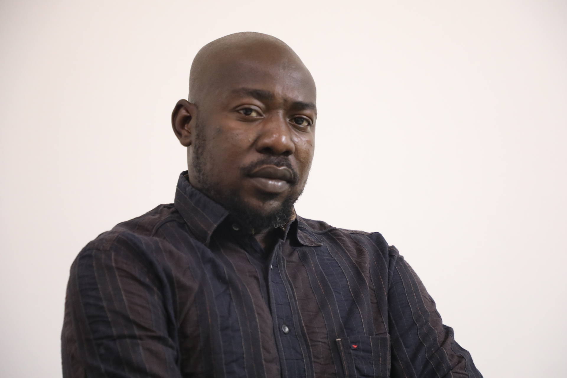 Photo of Alanosi in a black shirt against a white background.