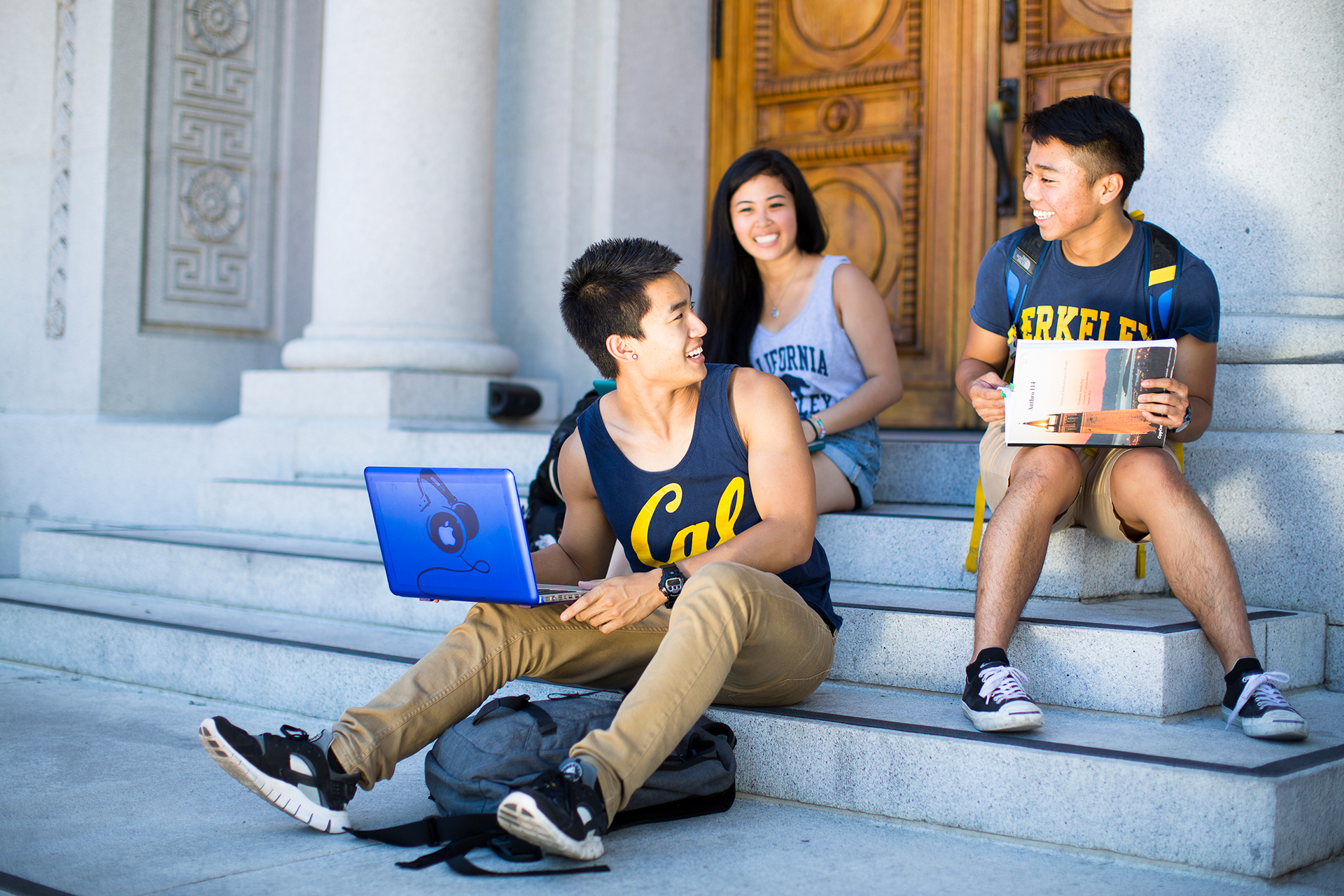 Photo of three smiling students sitting on the steps.