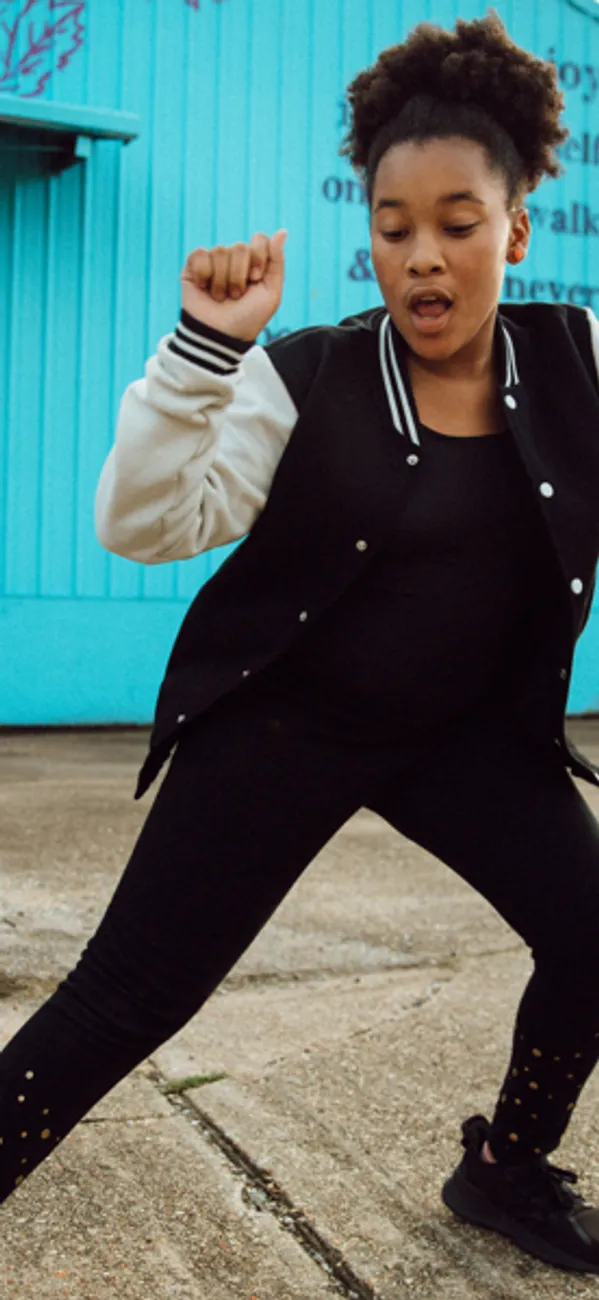 A girl dancing in front of a blue garage door outside