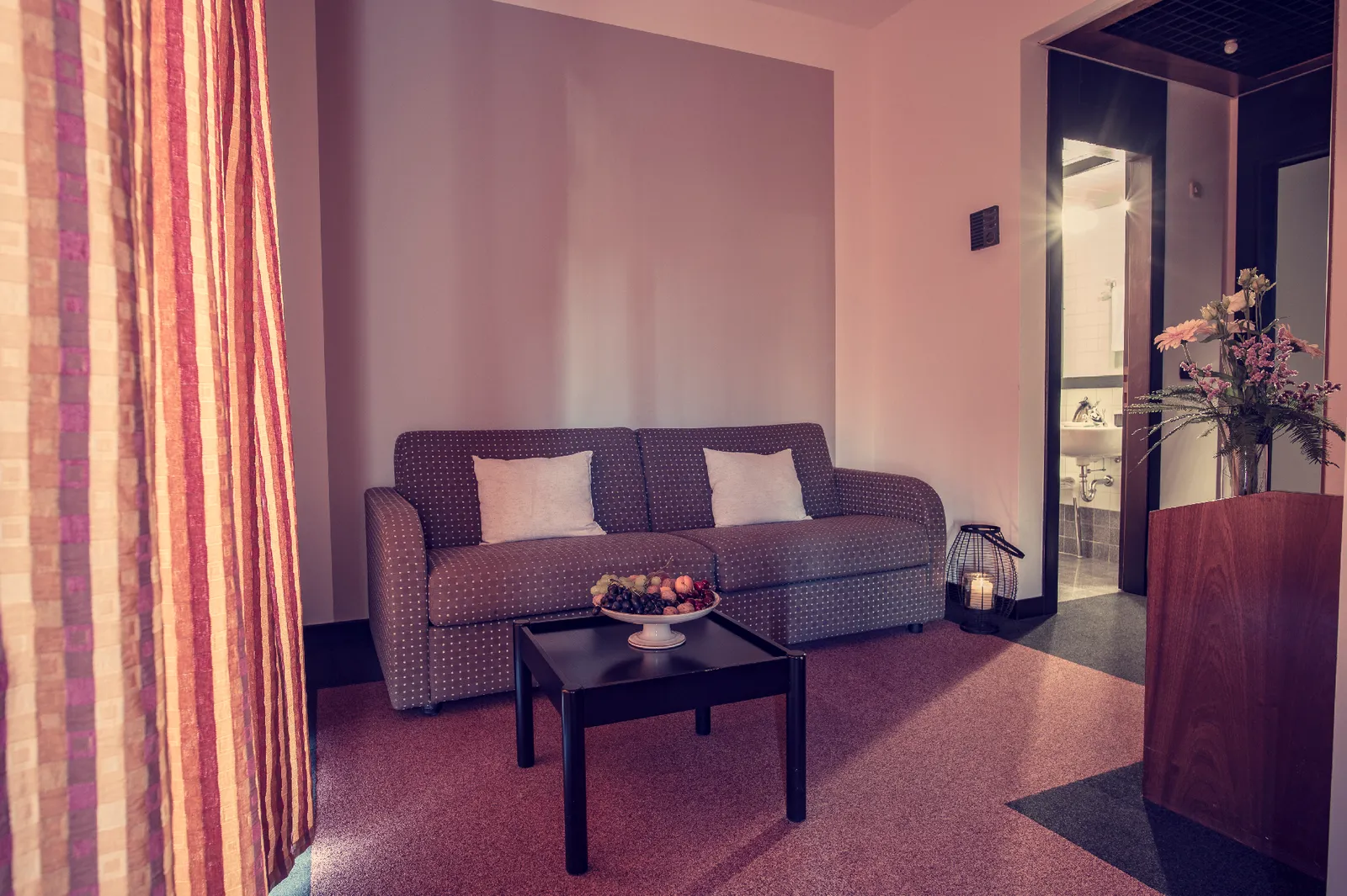 Living room with sofa, coffee table with fruit and fresh flowers.