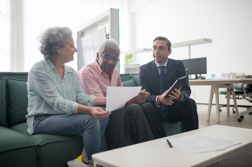 older couple sitting in their living room with agent discussing finances