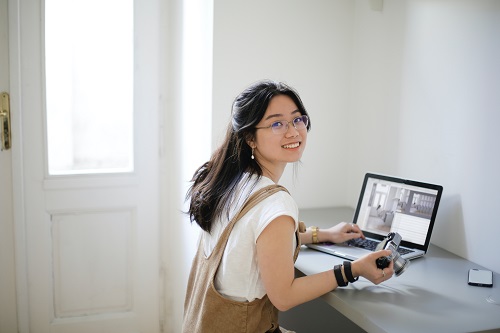 Photo of woman smiling with camera and laptop