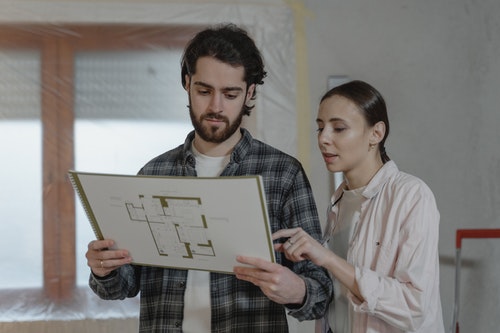 two people examining remodeling blueprints person in black and white checkered shirt holding the blueprint