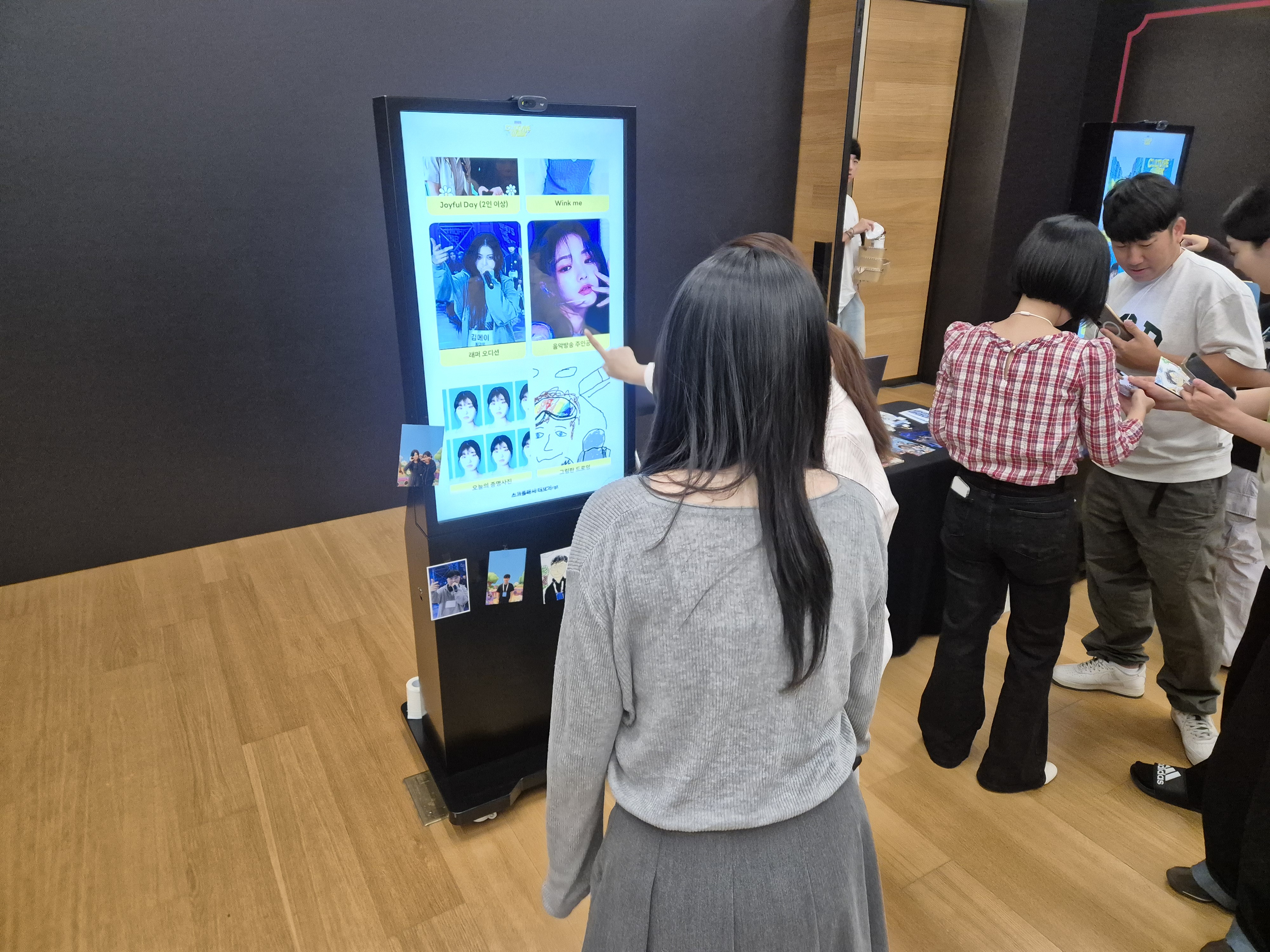 키오스크의 AI 필터 선택 화면을 터치하는 참가자