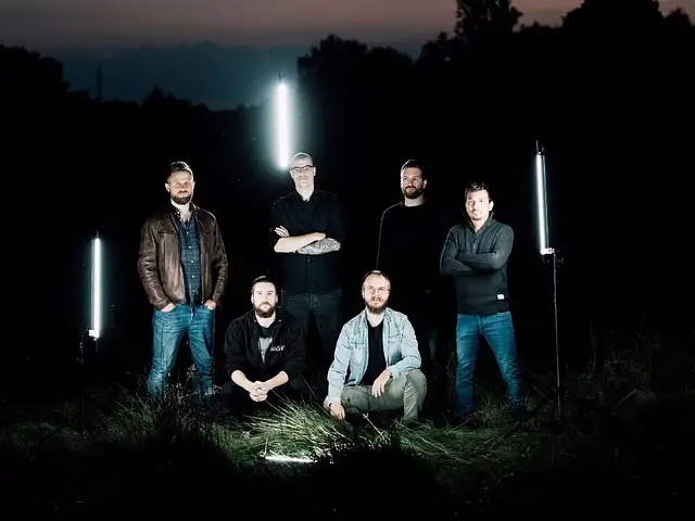 Wanheda (group of six people in casual clothes) standing in front of three neon lights on a meadow at night.