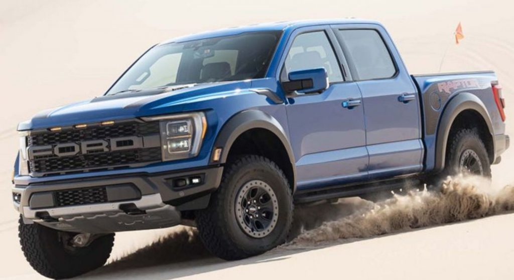 Ford F-150 Raptor azul en terreno arenoso.