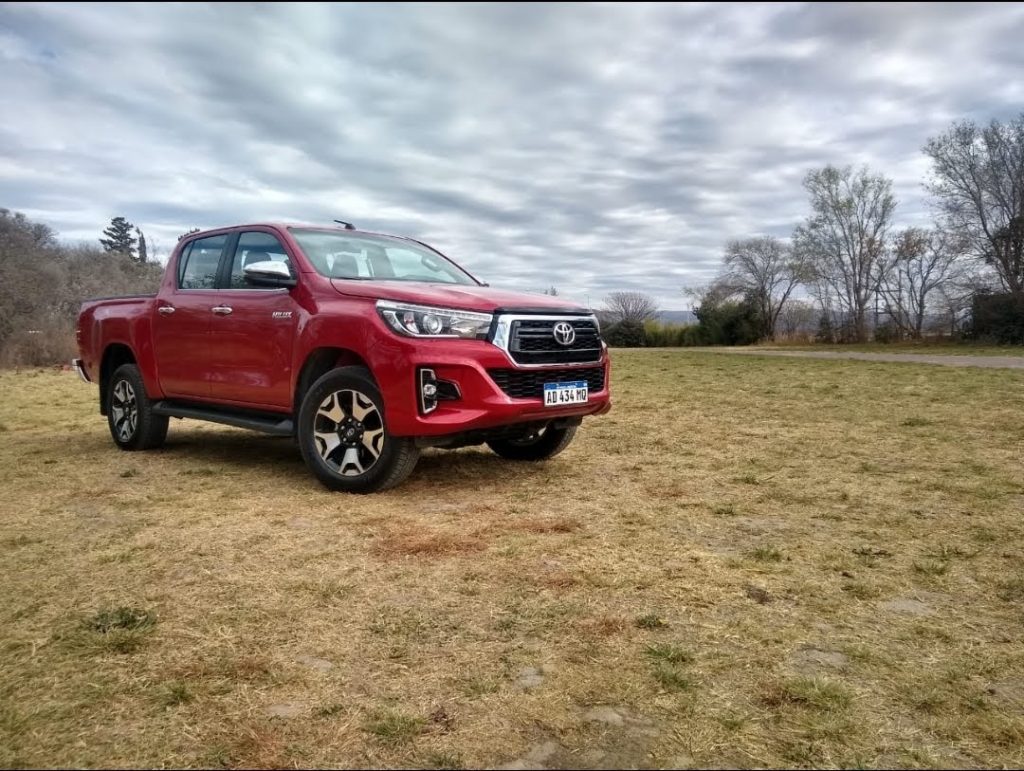 Lateral y frente Toyota Hilux roja.