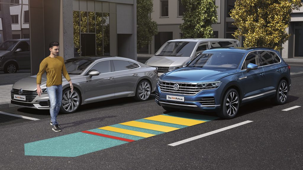 Auto con tecnología ADAS activada ante peatón que cruza la calle.