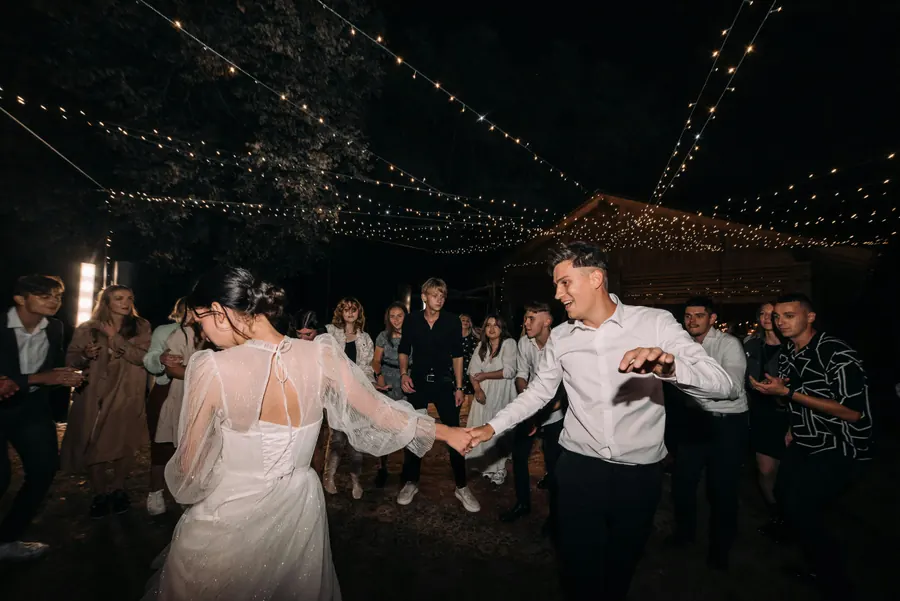 A couple dancing outside beneath warm string lights