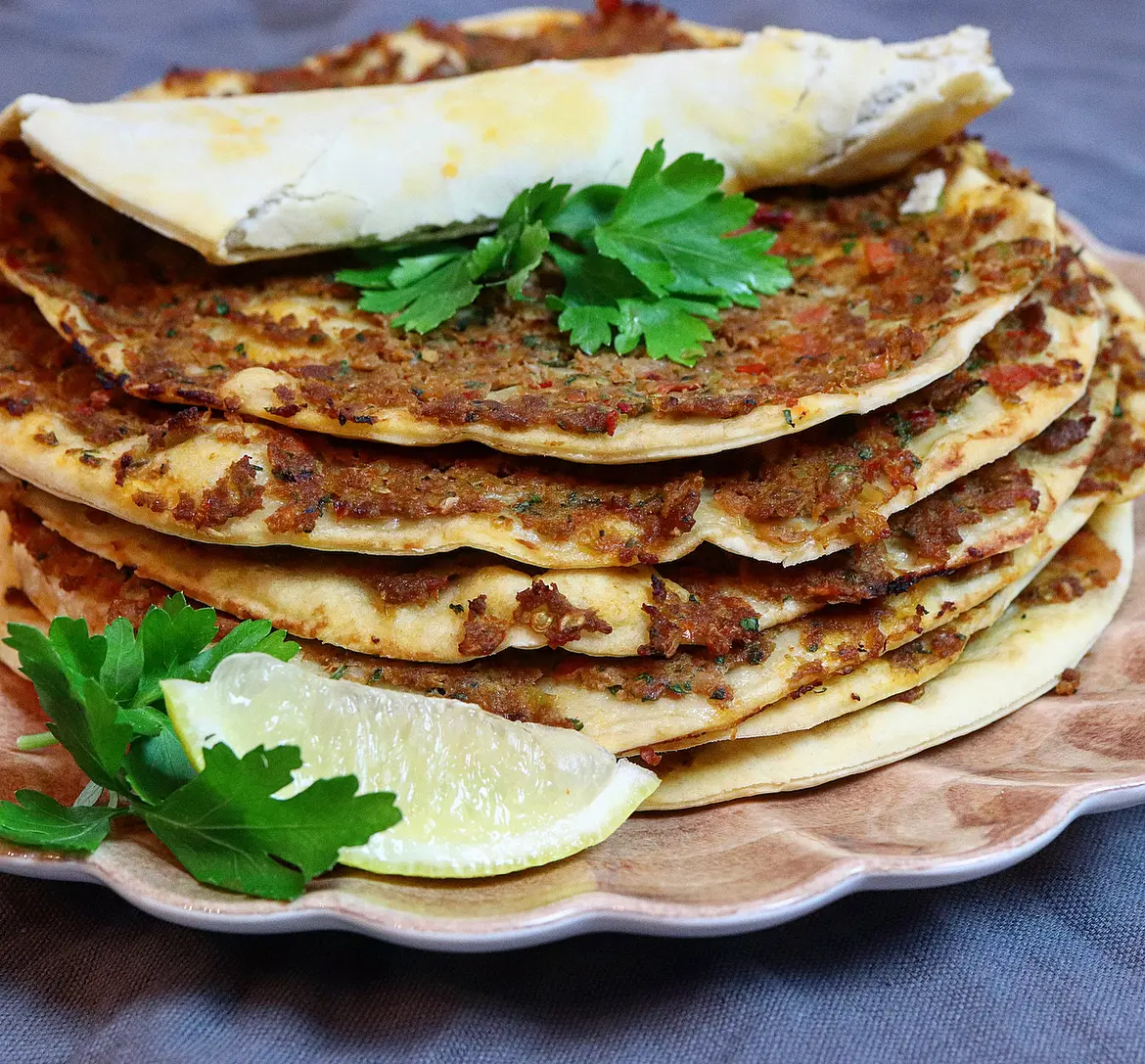 Stack av turkiska pidebröd med köttfärs, persilja och citron.