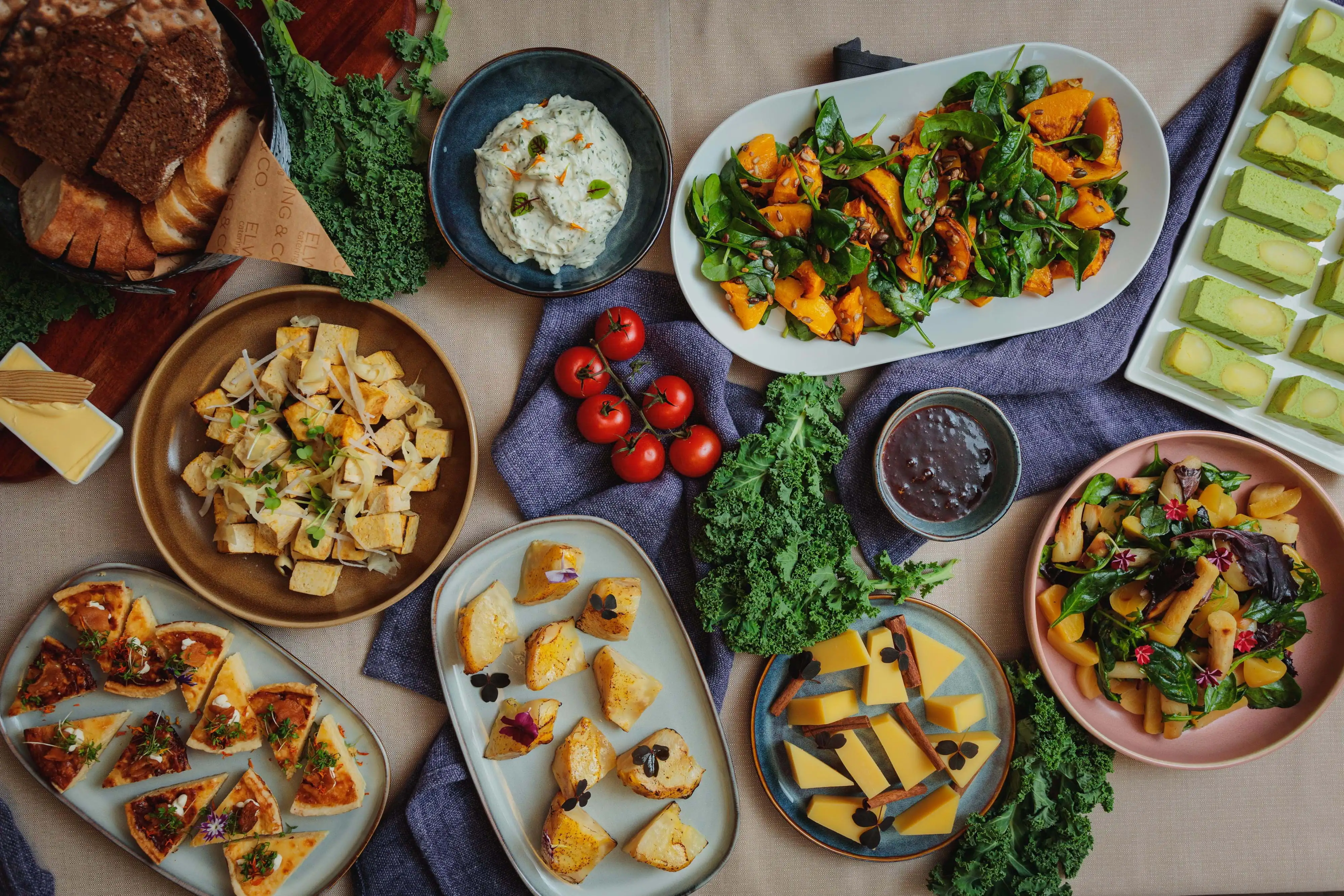 Ovanifrån: Bröd, tofu, sås, pumpa- & spenatsallad, grönsaksrätter, ost & kål.