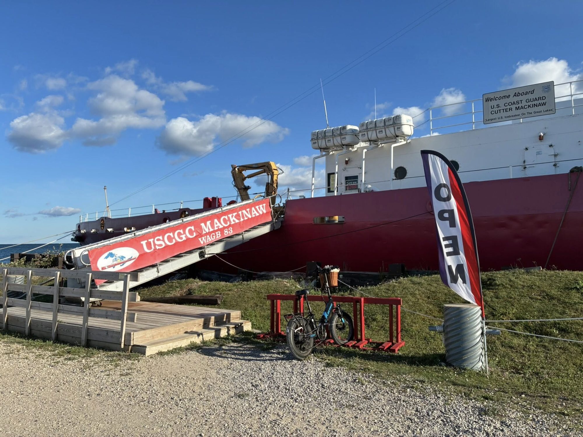 USCGC Mackinaw WAGB 83 museum ship docked with an Open flag and welcome gangway sign reading 'Welcome Aboard U.S. Coast Guard Cutter Mackinaw.'