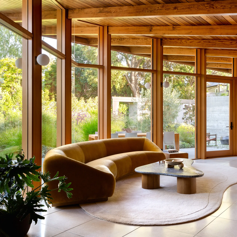 Curved furniture and rugs fit the irregular shape of the living room of the home.