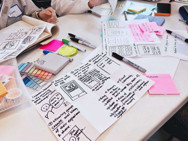 A photo of an assortment of Post-Its and small storyboards written in sharpie placed on a table.