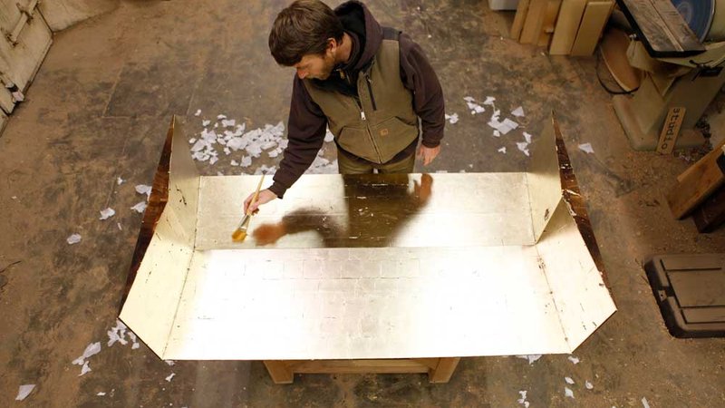 Bay Area furniture designer and CCA alumnus Florian Roeper puts the finishing touches on a gold-leafed surface in his Alameda atelier.